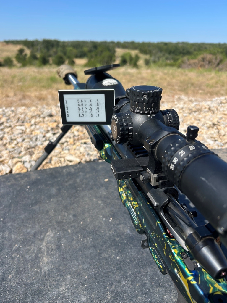 Precision rifle with a dope card showing target distances and ballistic corrections
