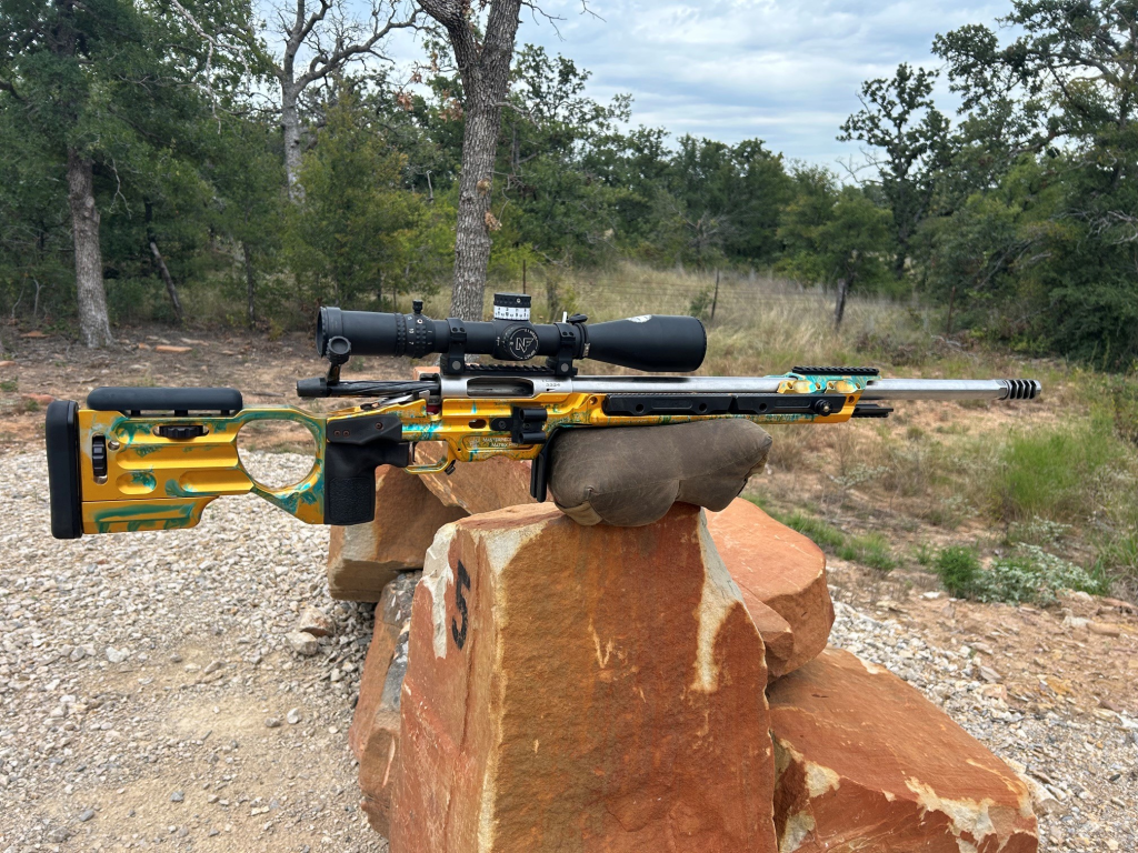 Precision rifle balanced on rocks near the front of the magazine well