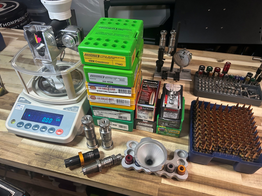Precision rifle reloading equipment, dies, bullets and measuring tools on a loading bench