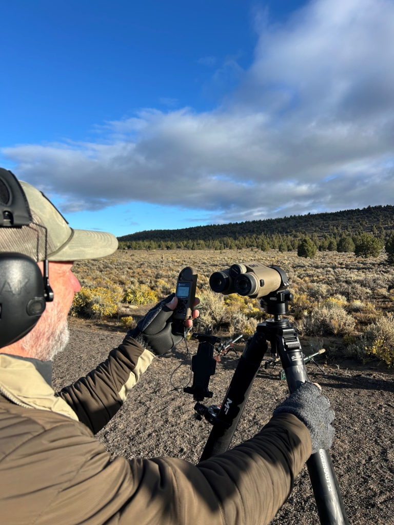 Shooter measuring wind and observing terrain before a long-range shot